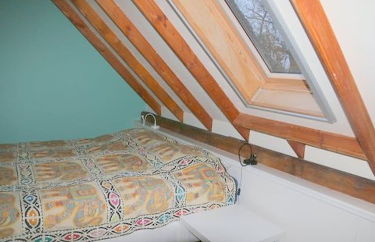 Bedroom with skylight in cottage in Heeten, Salland, with colorful blankets.