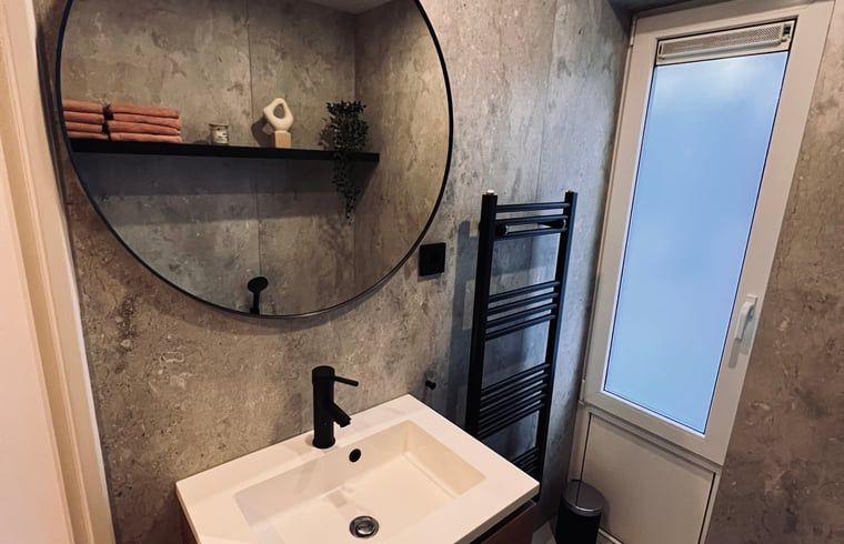 Badezimmer mit rundem Spiegel in einem Ferienhaus in Hellendoorn, Overijssel.