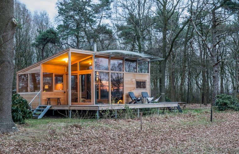 Vakantiehuis in Lettele bij zonsondergang, omringd door bomen in Salland, Overijssel.