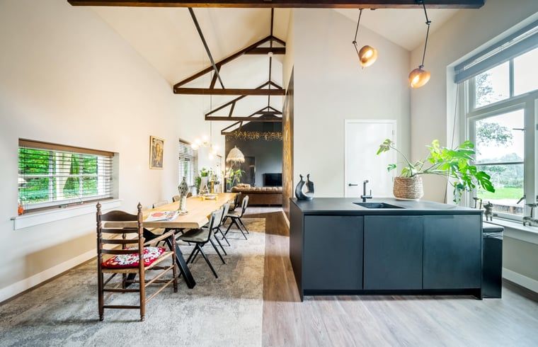 Open keuken en eetruimte in Vakantiehuis in Diepenveen, met houten balken en uitzicht op de tuin.