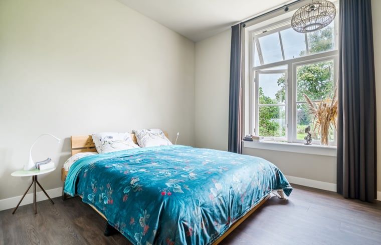 Slaapkamer in Vakantiehuis in Diepenveen met comfortabel bed en uitzicht op de groene omgeving van Salland.