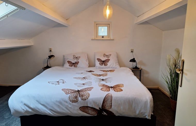 Knusse zolderkamer in Vakantiehuis in Diepenveen, met beddengoed in vlinderprint en gezellige sfeer.