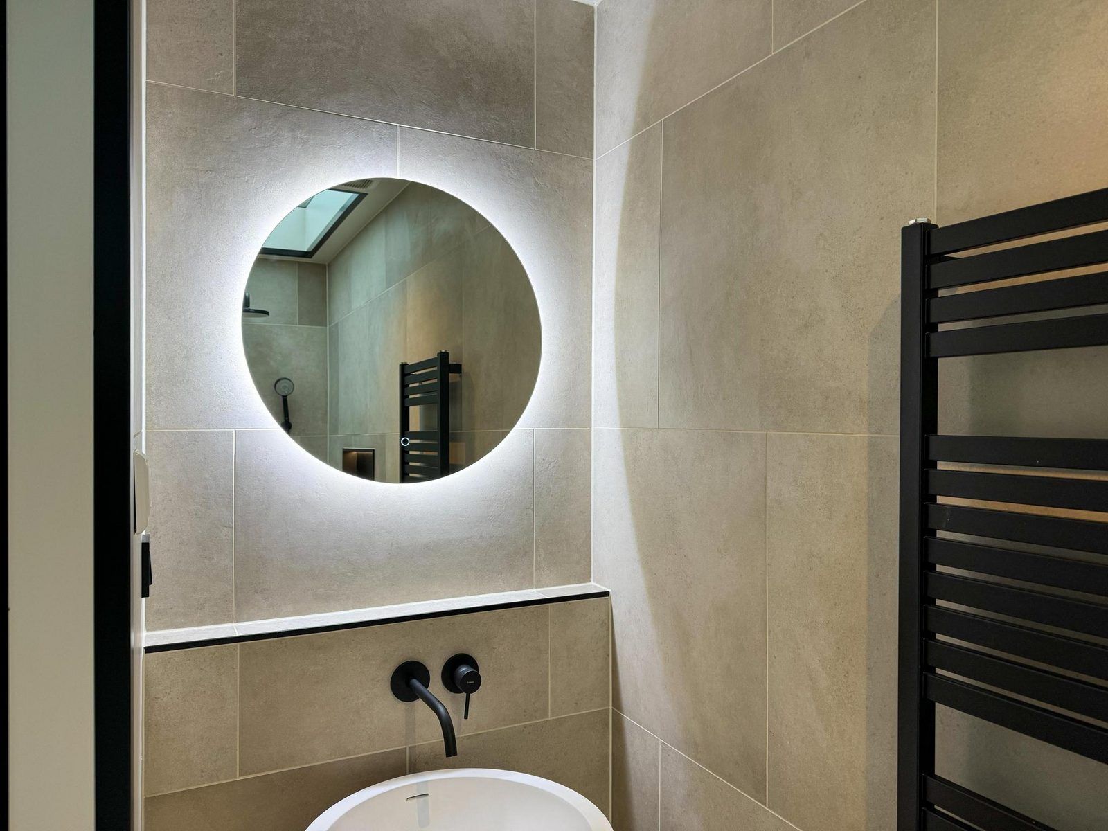 Elegantes Badezimmer in der Hill Lodge Glamping Lodge, Beerze, mit beleuchtetem Spiegel und Waschbecken.