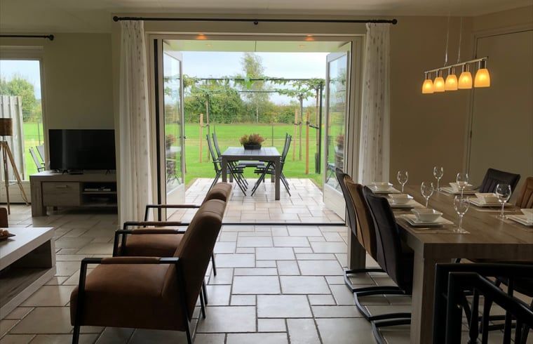 Geraeumiges Wohnzimmer des Ferienhauses in Beerze, Vechtstreek, Overijssel mit Fluegeltueren zum Garten.