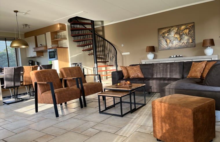 Modernes Wohnzimmer im Ferienhaus in Beerze, Overijssel, mit bequemen Sitzgelegenheiten und Treppe zum Obergeschoss.