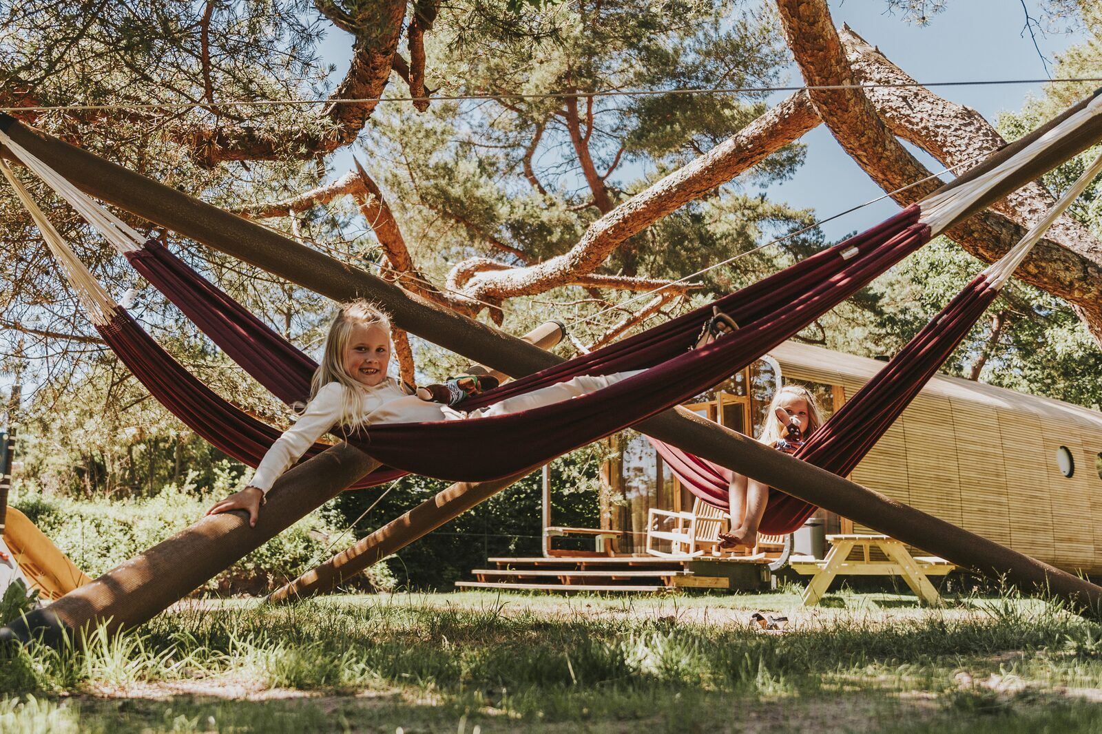 Kinder entspannen sich in Haengematten im Wikkelhouse XL, Beerze, umgeben von der Natur der Vecht-Region.