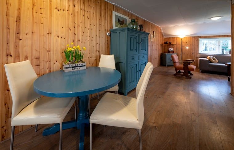 Gezellige binnenruimte van Vakantiehuisje in Balkbrug, Vechtstreek, Overijssel met houten muren en een blauwe tafel voor een knusse sfeer.
