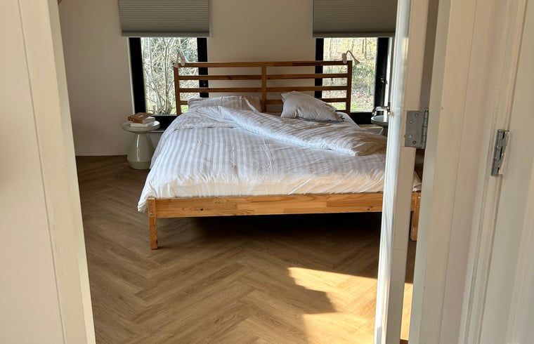 Ruime slaapkamer met houten details in Huisje in Balkbrug