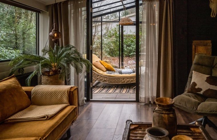 Stilvolles Wohnzimmer des Ferienhauses in Rheezerveen, Vechtstreek, Overijssel mit moderner Einrichtung und Zugang zum Wintergarten.