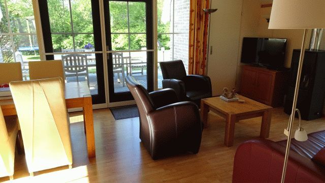 Gezellige woonkamer in vakantiehuis AA-Reestryck, IJhorst, Overijssel met uitzicht op groene tuin en ruime zithoek.