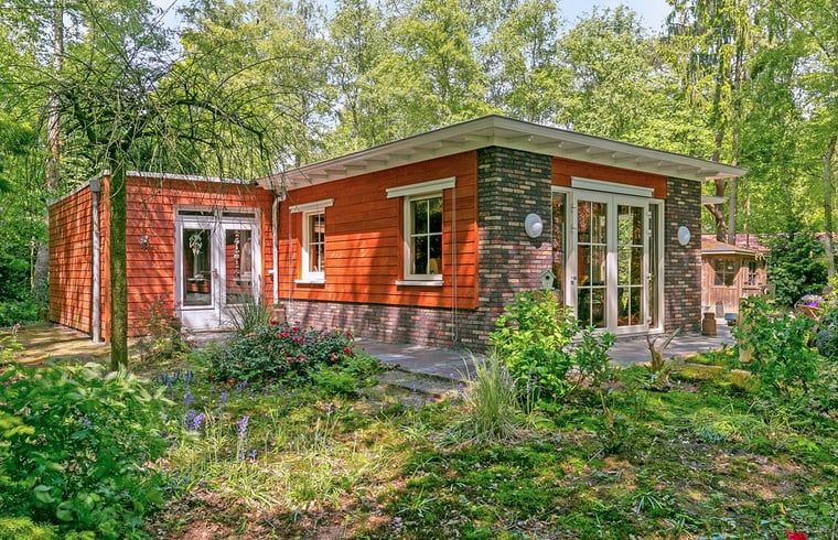 Rode gevel van Vakantiehuis in Bergentheim, omgeven door bloeiende tuinen in de Vechtstreek, Overijssel.