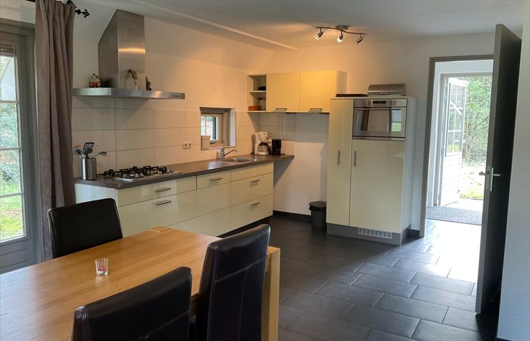 Moderne Kueche im Ferienhaus in Lemele, Vechtstreek, Overijssel mit geraeumiger Essecke und Blick auf die gruene Umgebung.