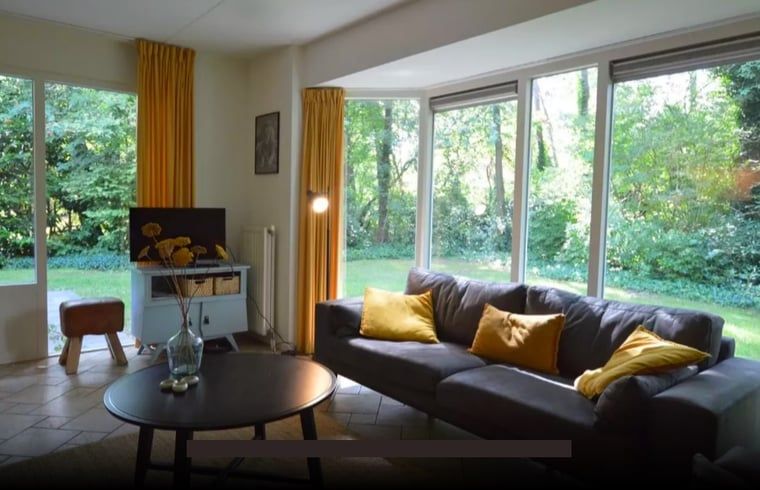 Lichte woonkamer van vakantiehuis Huisje in Lemele, Overijssel met grote ramen en groene omgeving.