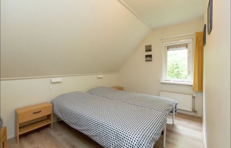 Slaapkamer met tweepersoonsbed en kleurrijke inrichting in Huisje in Lemele, Overijssel.