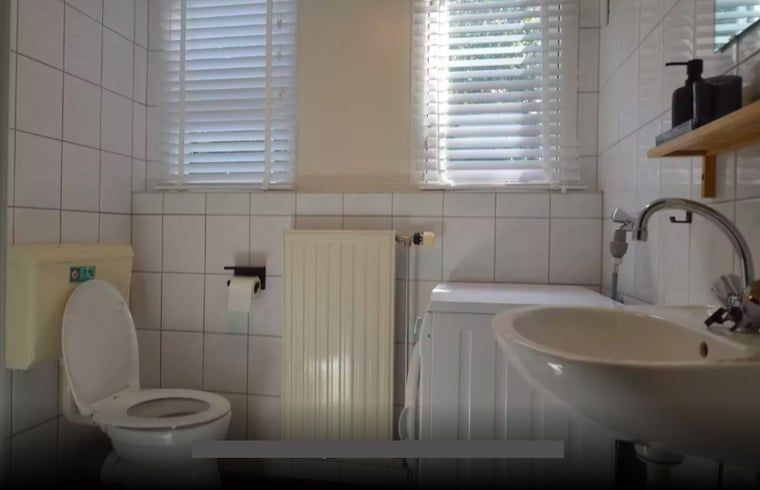 Ruime badkamer met bad in Huisje in Lemele, Overijssel voor ultiem comfort.