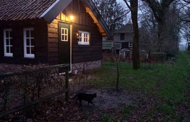 Sfeervol verlicht vakantiehuis in Brucht, Vechtstreek, Overijssel in de avondschemering.