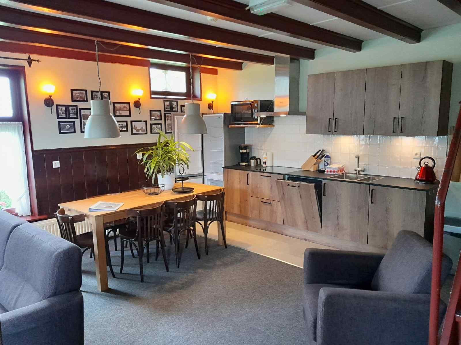 Modern kitchen and dining area in vacation home OV602 in Giethoorn with wooden beams.