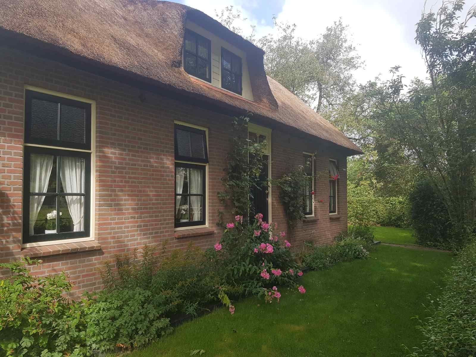 Exterior of vacation home OV602 in Giethoorn with colorful flowers and green garden.