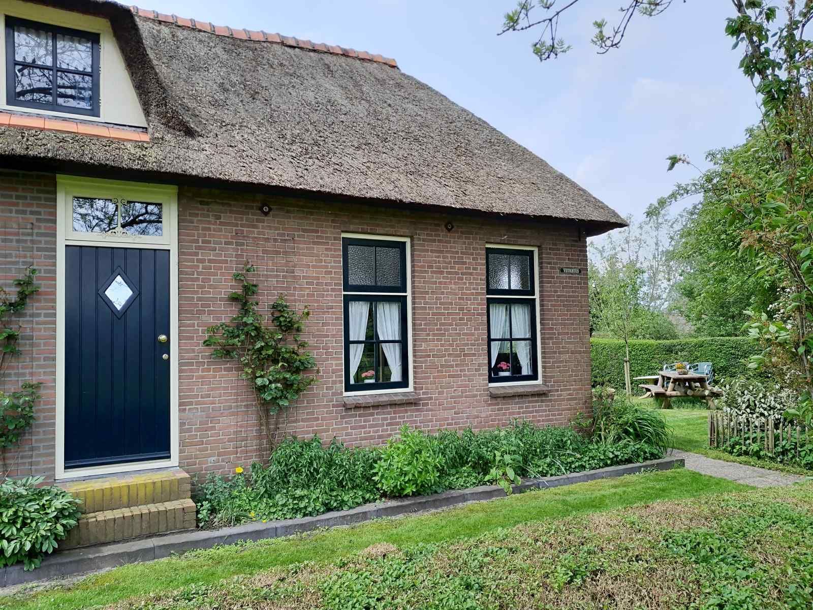 Charming entrance to vacation home OV602 in Giethoorn with thatched roof and green facade.