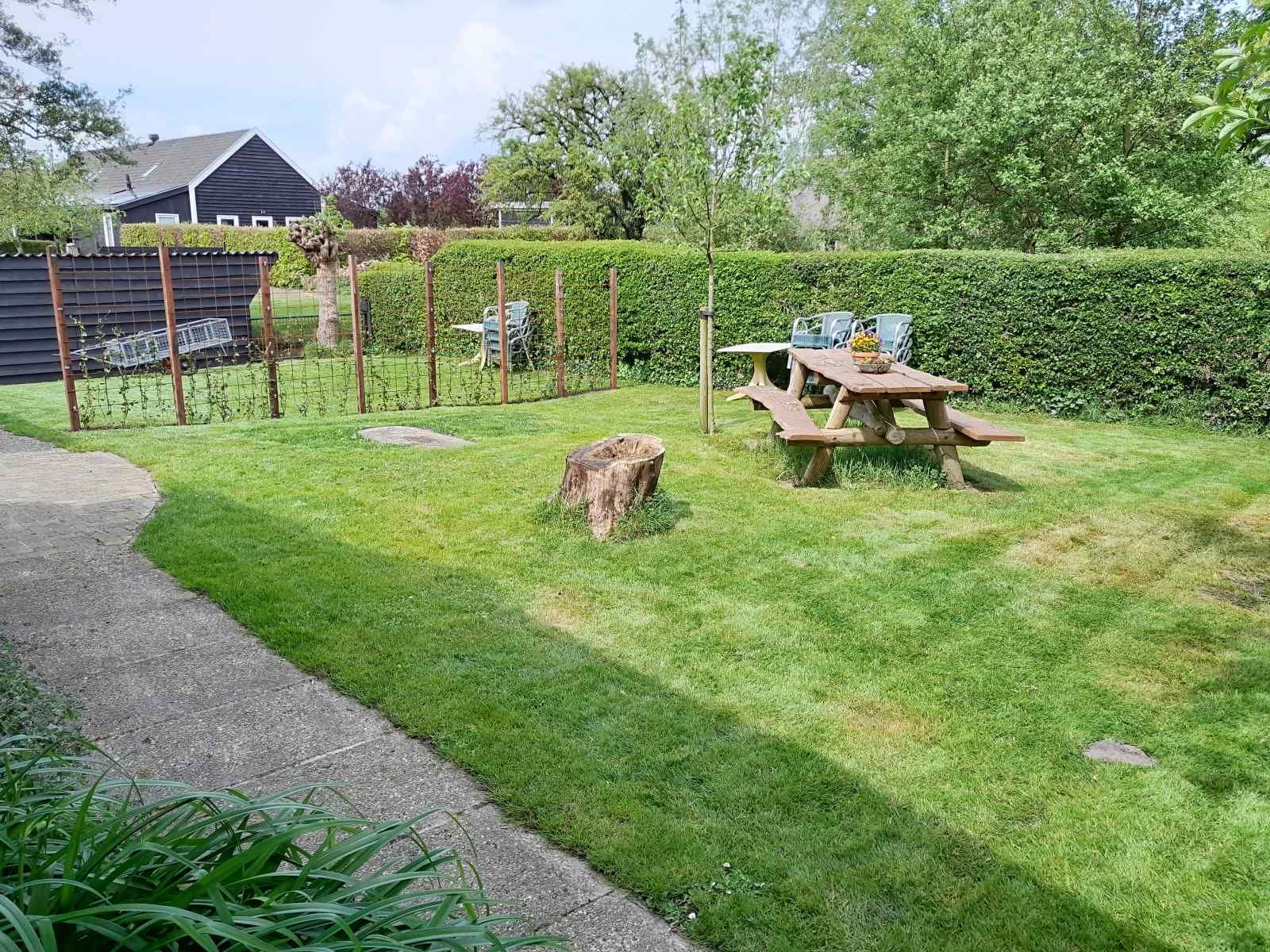 Spacious green garden of vacation home OV602 in Giethoorn with wooden picnic table.