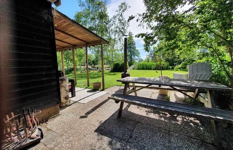 Aussenbereich des Ferienhauses in Giethoorn, Nordwest Overijssel, mit einem gemuetlichen Picknicktisch und Blick auf den gruenen Garten.