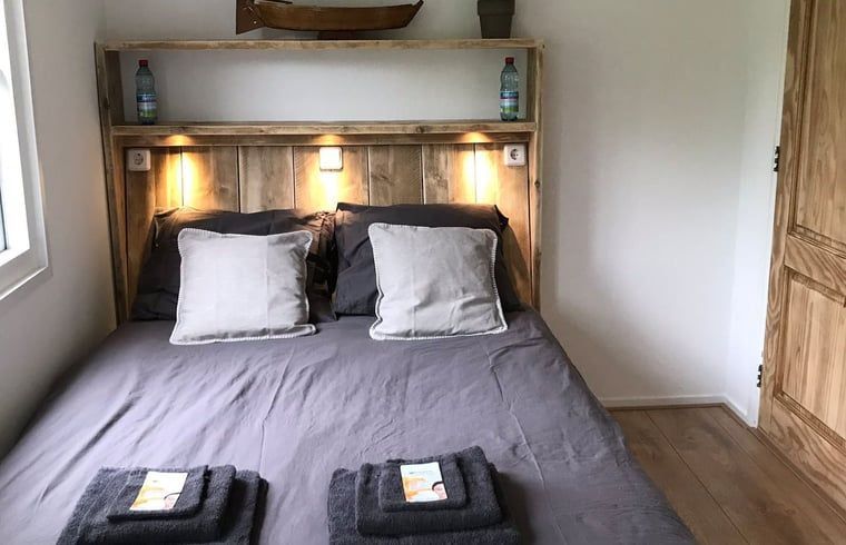 Gemuetliches Schlafzimmer im Ferienhaus in Giethoorn, Overijssel, mit einem Doppelbett und stimmungsvoller Beleuchtung fuer eine gute Nachtruhe.