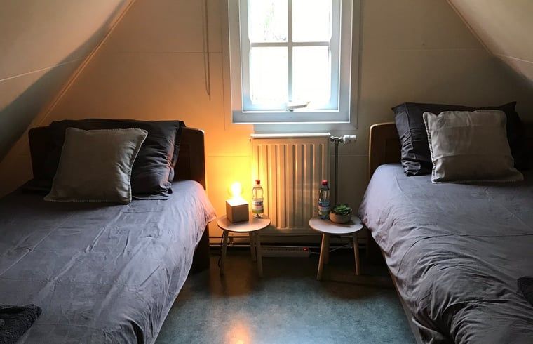Schlafzimmer im Dachgeschoss eines Ferienhauses in Giethoorn, Nordwest Overijssel, mit zwei Einzelbetten und einem gemuetlichen Ambiente.