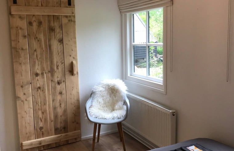 Gemuetliche Ecke im Ferienhaus in Giethoorn, Overijssel, mit einem bequemen Stuhl und Gartenblick zum Entspannen.