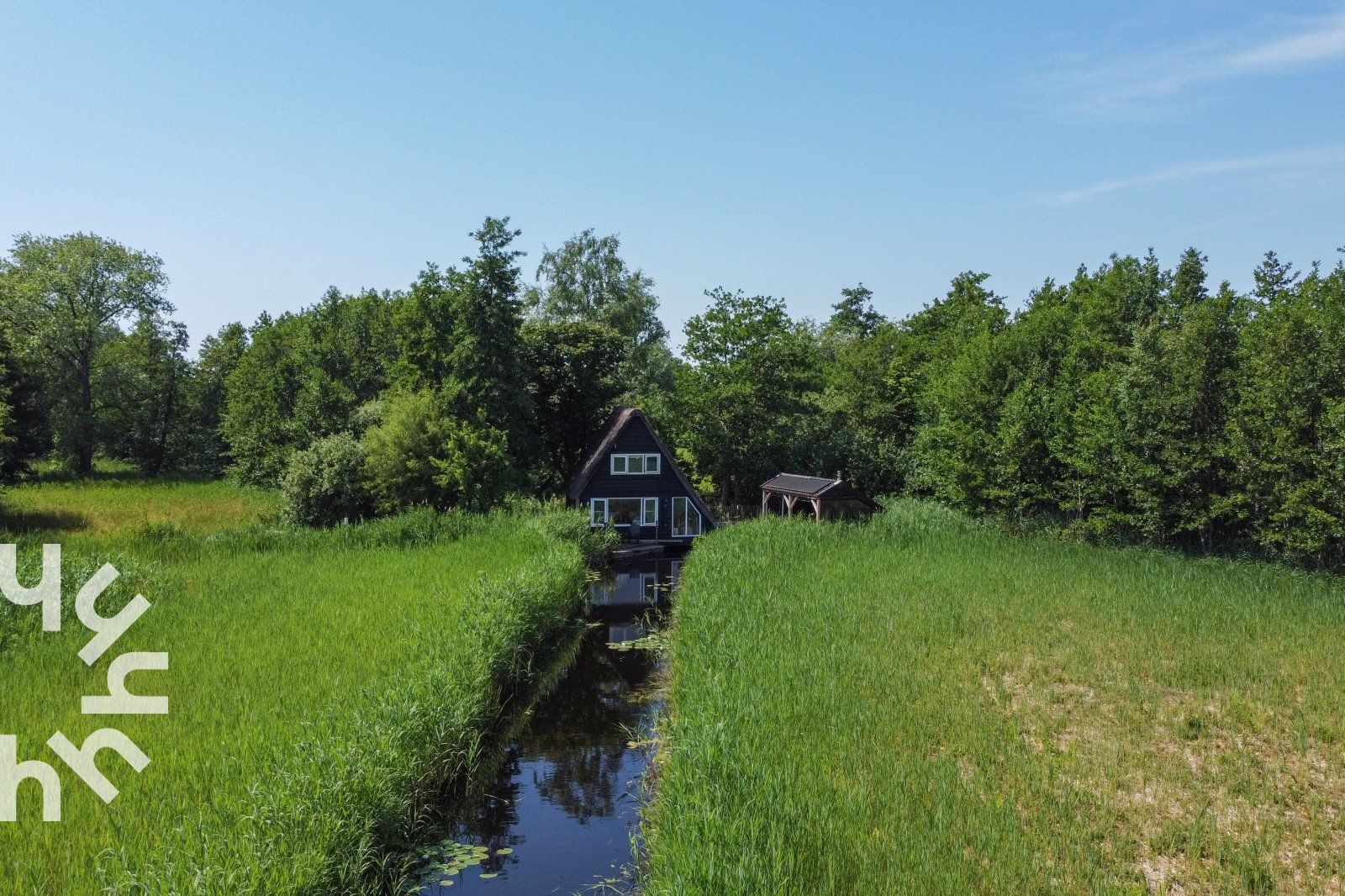 Ferienhaus OV465 in Giethoorn, umgeben von Gruen und Wasser.