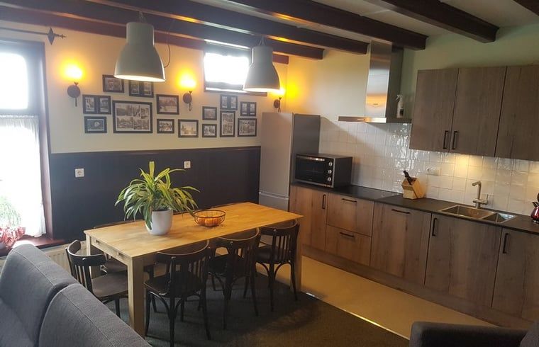 Eetkamer met houten tafel en moderne keuken in Vakantiehuisje in Giethoorn, Noordwest Overijssel, Overijssel.