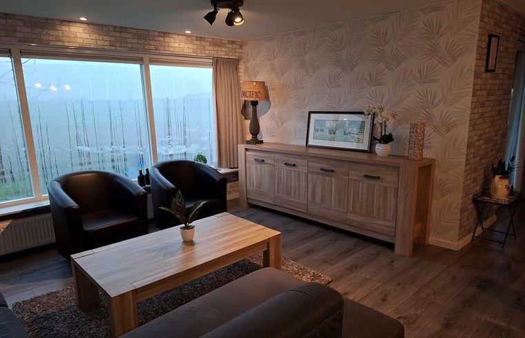 Cozy dining room in a vacation home in Zwartsluis, Overijssel, with modern interior and view of the porch for a relaxing stay.