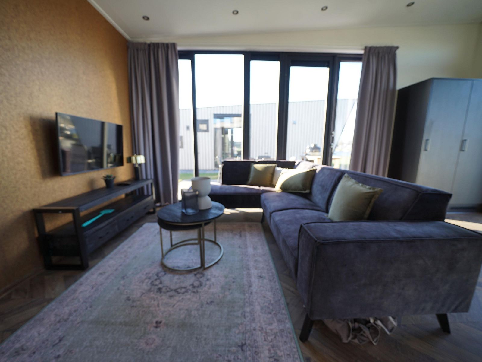 Gemtliches Wohnzimmer im freistehenden Haus in Kampen, Nordwest-Overijssel, mit bequemem Sofa und groen Fenstern fr viel Licht.