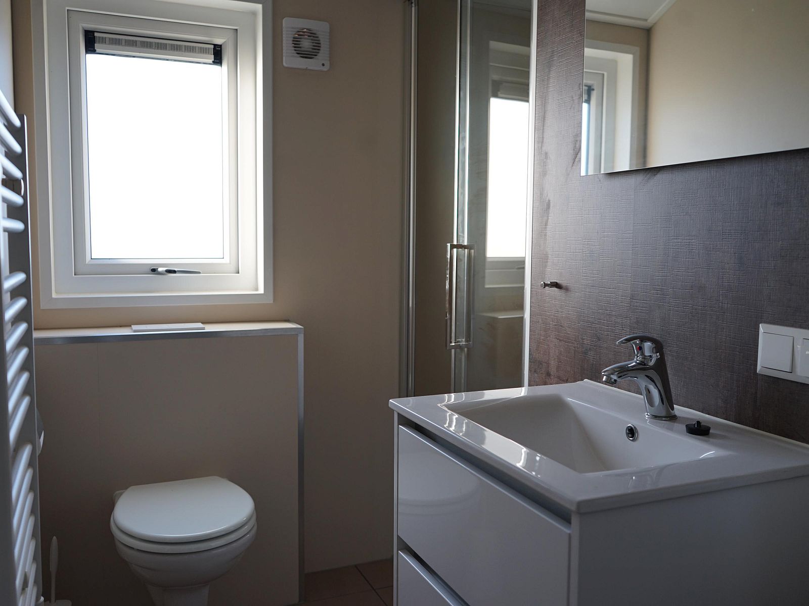 Modernes Badezimmer im freistehenden Haus in Kampen, Overijssel, mit schlichtem Waschbecken und gerumiger Dusche fr einen komfortablen Aufenthalt.