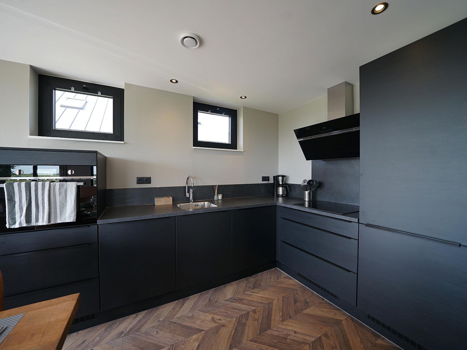 Modern kitchen in the detached house in Kampen, vacation home in Northwest Overijssel, with stylish black cabinets and wooden flooring.