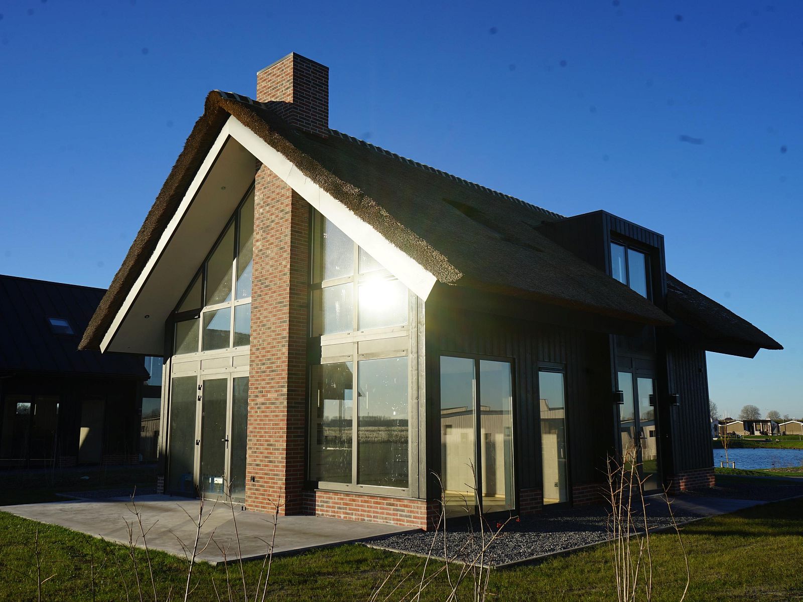 Vrijstaande woning in Kampen, een vakantiehuis in Noordwest Overijssel, met moderne architectuur en rieten dak, omringd door natuur.