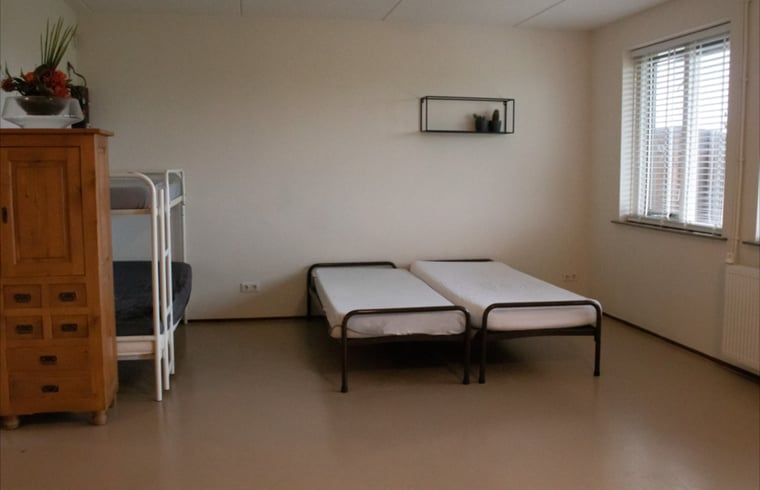 Ruime slaapkamer in Huisje in Steenwijk, Overijssel, met stapelbed en twee eenpersoonsbedden voor een ontspannen verblijf.