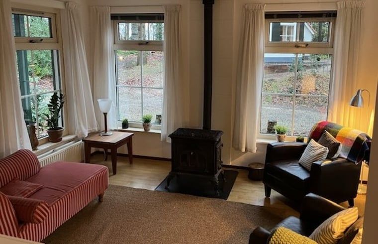Warme Sitzecke mit Holzofen im Ferienhaus in IJhorst, ideal fuer gemuetliche Abende im Nordwesten der Overijssel.