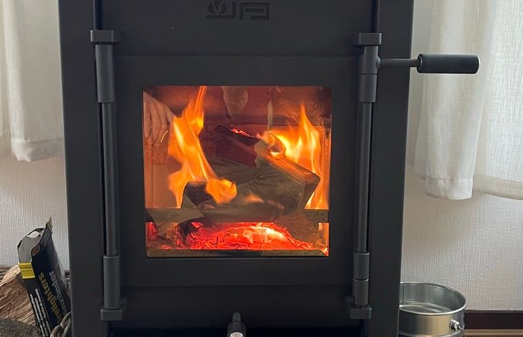 Gemuetliche Leseecke mit Sessel und Holzofen im Ferienhaus in IJhorst, ideal fuer Erholung im Nordwesten der Overijssel.