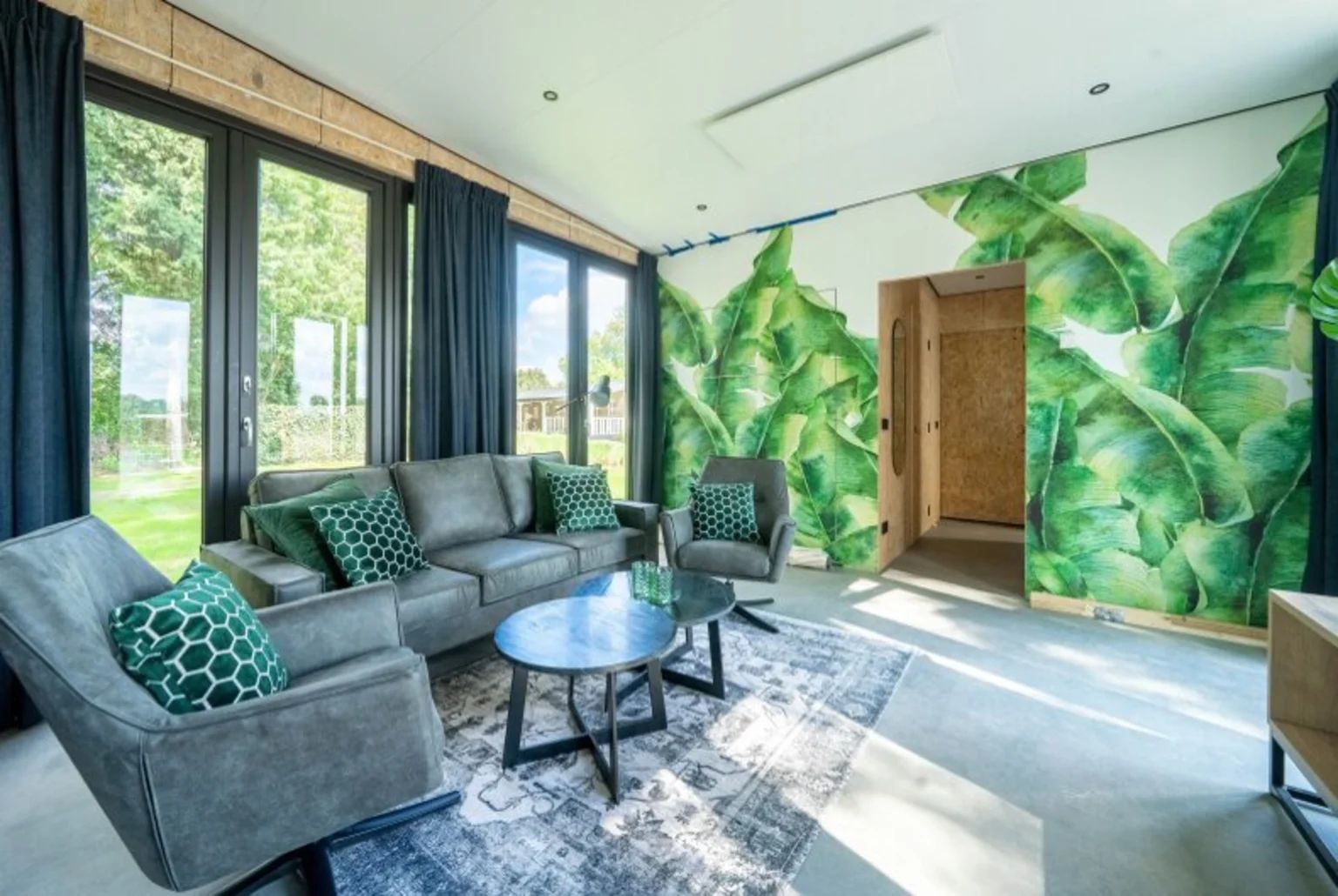 Modernes Wohnzimmer in einem freistehenden Haus in IJhorst, Overijssel, mit grnen Akzenten und Blick auf den Garten.