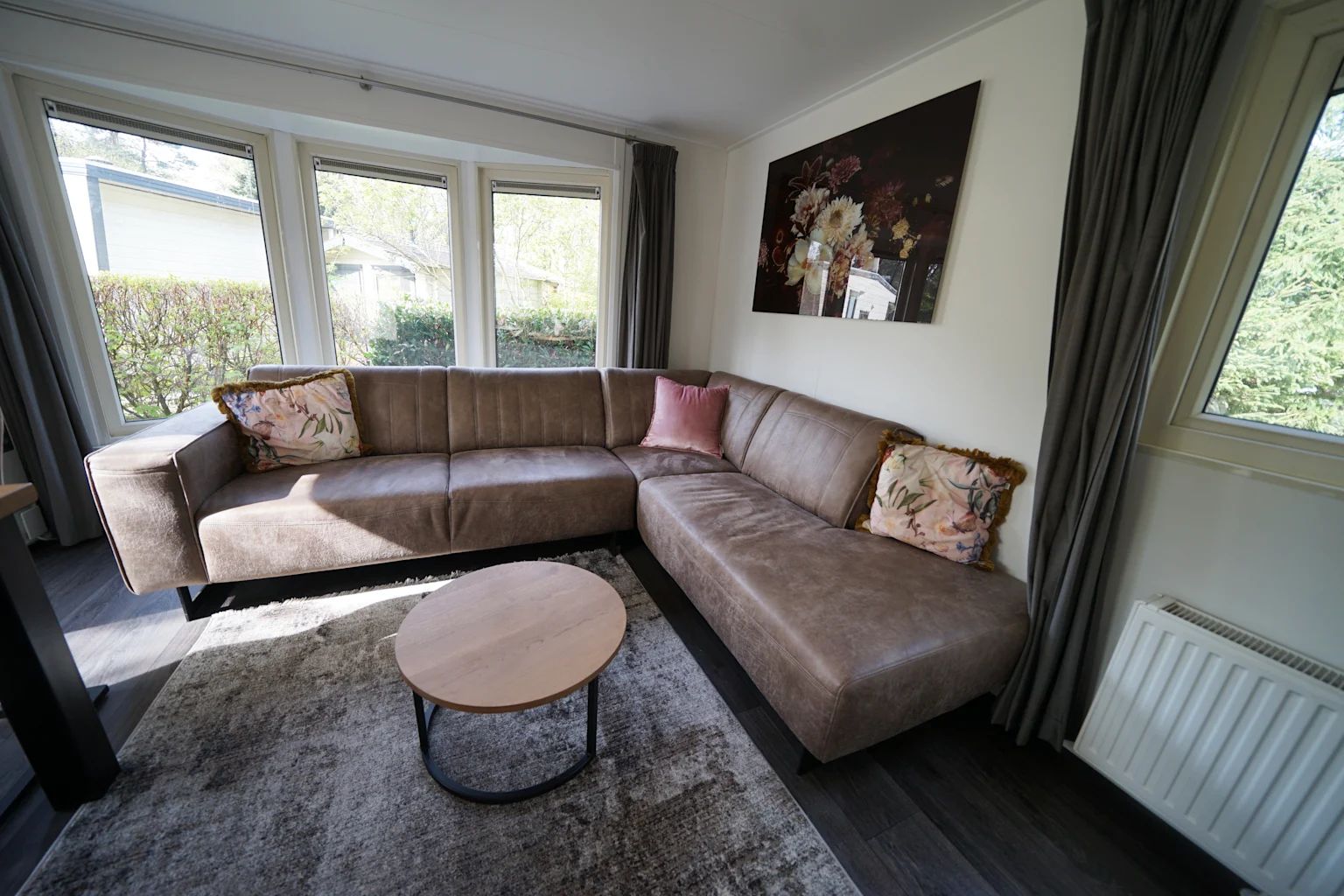 Gezellige woonkamer in Vrijstaande woning in IJhorst, Overijssel, met comfortabele bank en uitzicht op de groene omgeving.