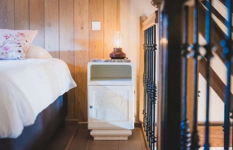 Nachtkastje met lamp in Vakantiehuis in Sint Jansklooster, Overijssel, voor een knusse sfeer.