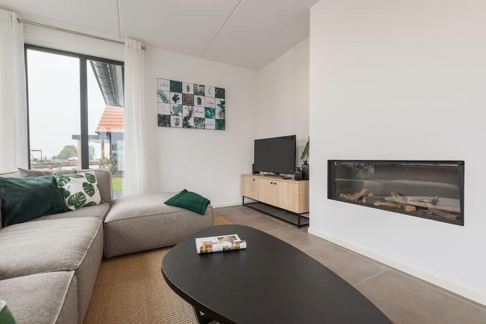 Gezellige woonkamer in Watervilla 8, een vakantiehuis in Ossenzijl, Noordwest Overijssel, met moderne inrichting en sfeervolle haard.