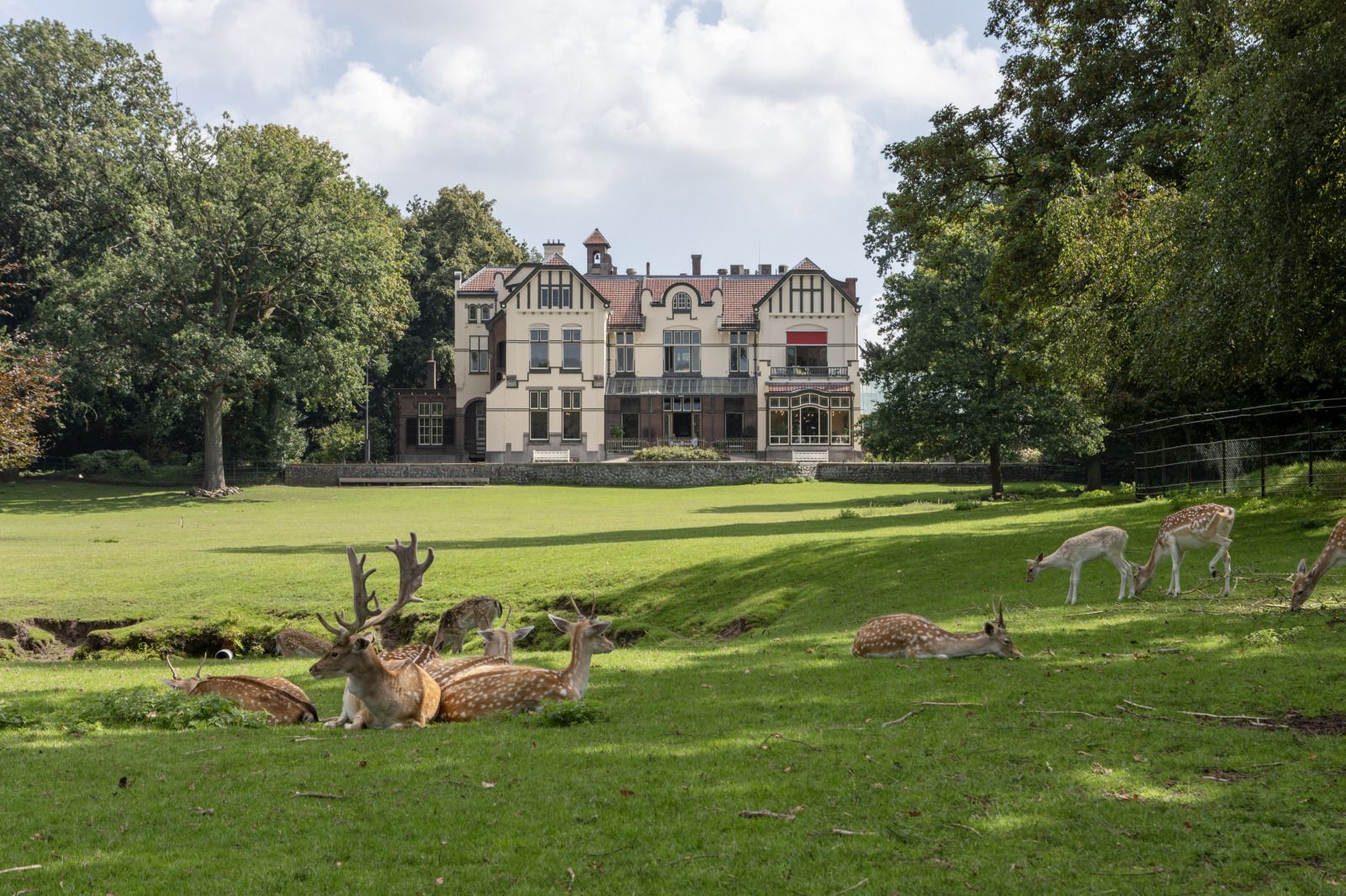 Lichtdurchfluteter Innenraum des Ferienhauses OV735 in Tuk, Overijssel, mit Blick auf den gruenen Garten und moderne Pendelleuchten.