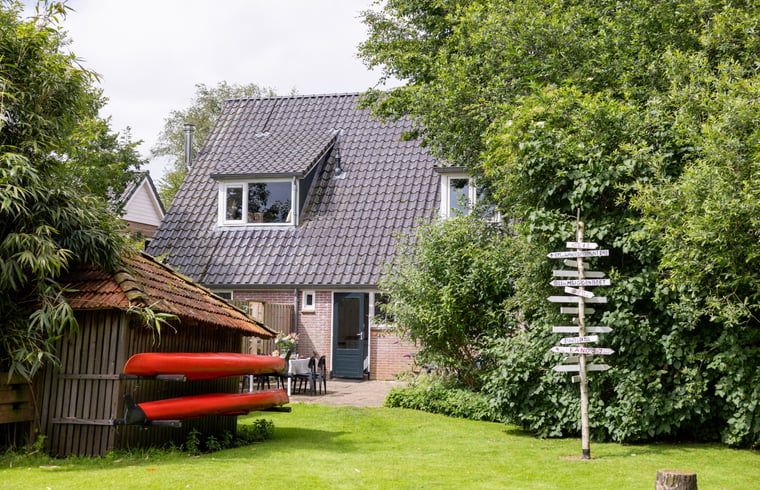 Buitenkant van Vakantiehuisje in Wetering, Overijssel. Traditioneel huis met groene omgeving en kano's.