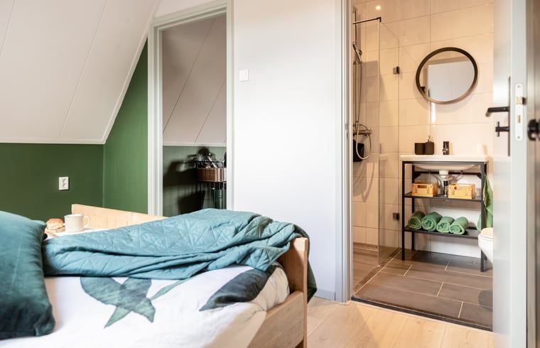 Slaapkamer met toegang tot badkamer in Vakantiehuisje in Wetering, Noordwest Overijssel. Praktisch en stijlvol.