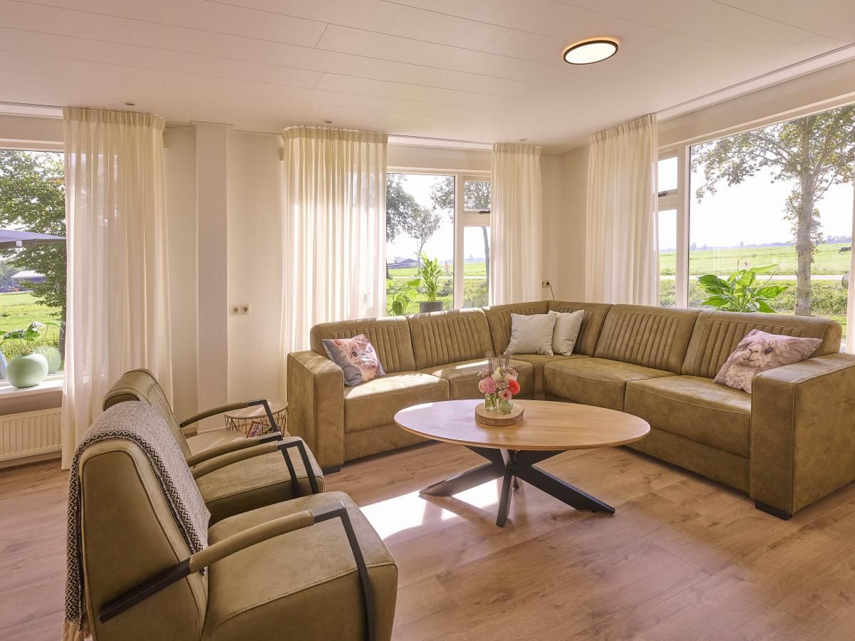 Lichte woonkamer in Alpa Casa vakantiehuis, Rouveen, Overijssel met uitzicht op de groene omgeving.