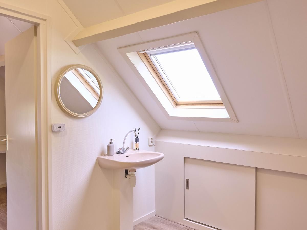 Badkamer op zolder in Alpa Casa vakantiehuis, Rouveen, Overijssel met dakraam en wastafel.