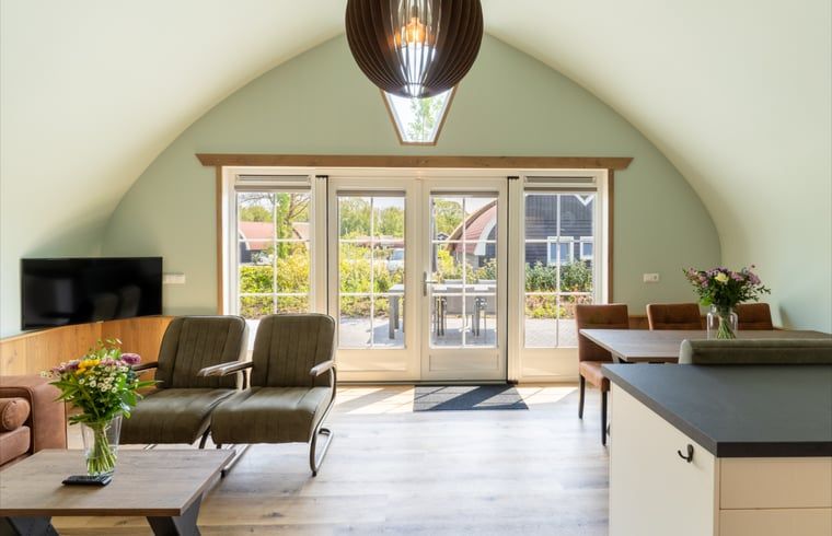 Helles Wohnzimmer im Ferienhaus in Baars mit Blick auf die Terrasse, gelegen in Overijssel.