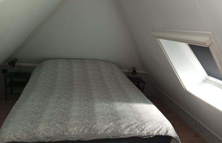 Knusse slaapkamer onder het dak van het vakantiehuisje in Staphorst, biedt comfort in Overijssel.
