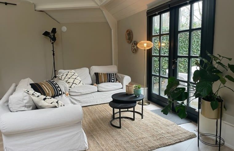 Stijlvolle woonkamer in Huisje in Tienhoven, vakantiewoning in Tienhoven, Utrecht, met comfortabele banken en veel licht.